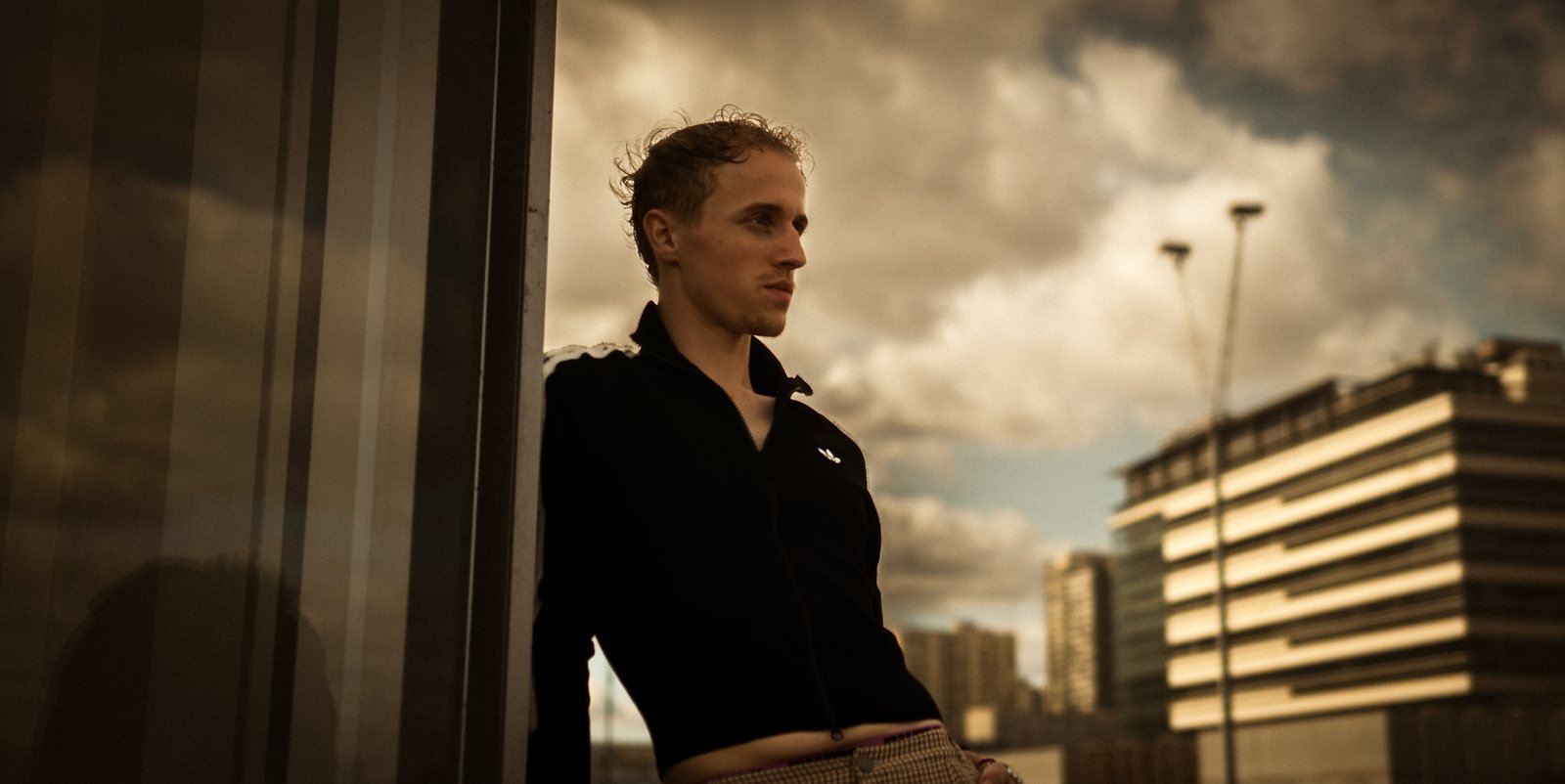 Léo Martin adossé à une vitre, sous un ciel chargé